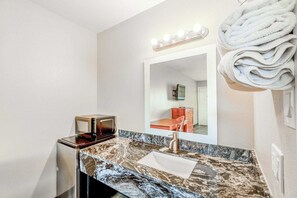 Un baño con tocador, lavamanos, espejo y toallero.