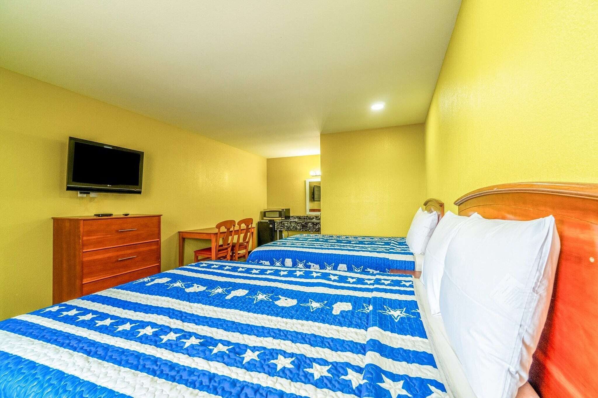 Une chambre d’hôtel avec un lit, une télévision, un bureau et une chaise.