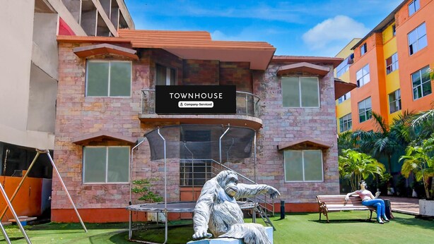 A building labeled 'TOWNHOUSE' with a balcony, a statue of a gorilla, and a person sitting on a bench. - Classic With Pool View Hotel Coral (Kanthi)