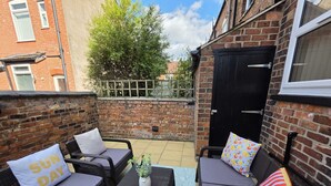 A patio with two sofas, a small table, and a potted plant. - Newly Refurbished
Suburban Luxe By Luxe Sleep (Stockport)