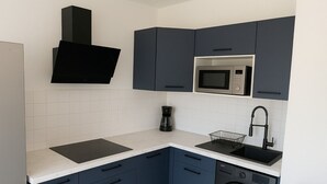Een kleine keuken met een magnetron, koffiezetapparaat, spoelbak en vaatwasser.