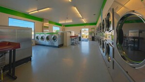 A laundromat with multiple washing machines, a folding station, and a window providing natural light.