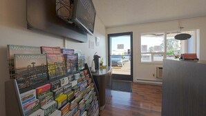 A reception area with a wall-mounted TV, a glass display of travel guides, and a door leading outside.