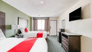 Habitación de hotel con dos camas, televisión, escritorio y armario.
