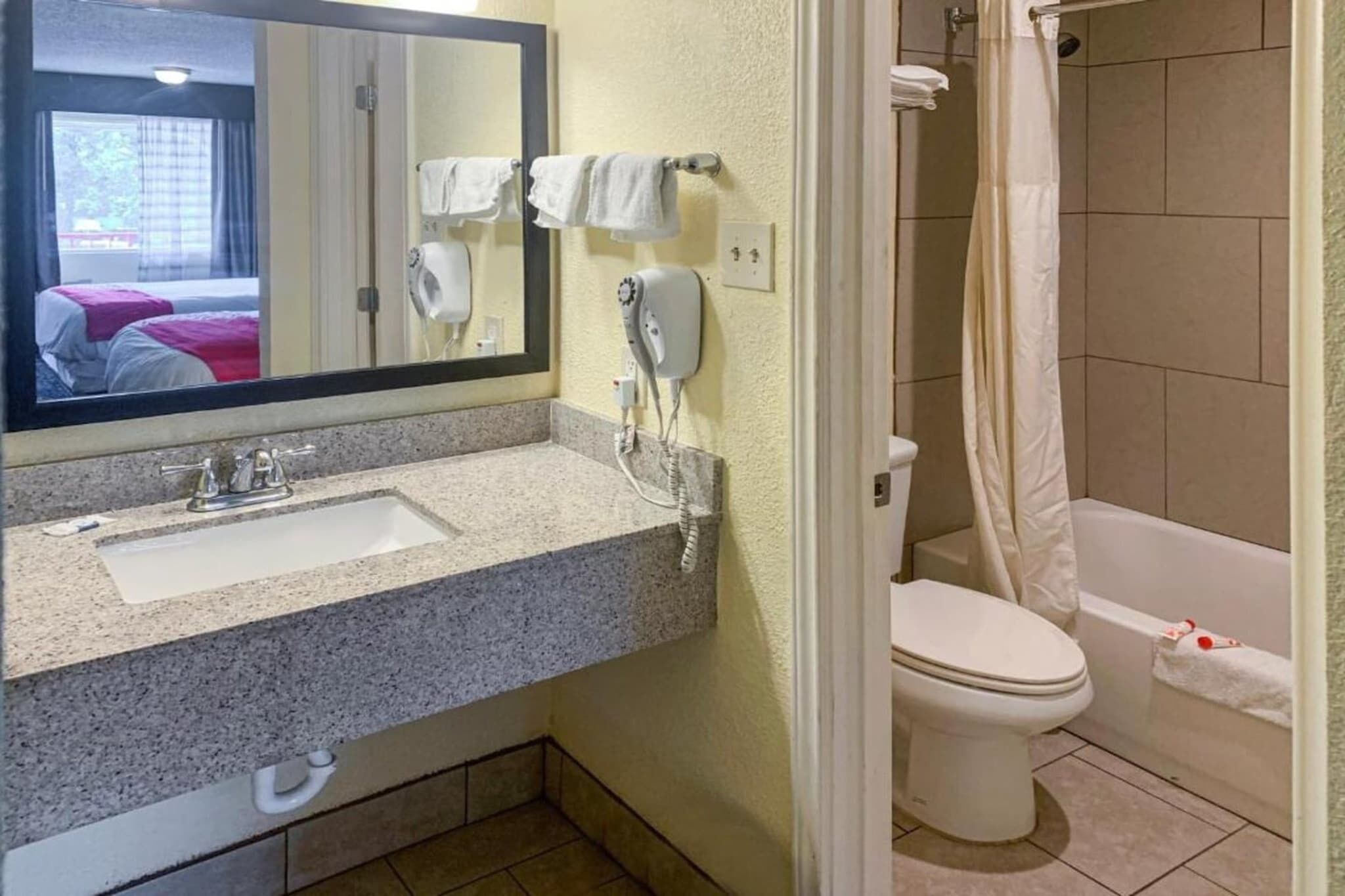Een badkamer met een wastafel, spiegel, haardroger en toilet.