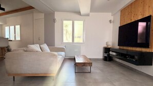 En moderne stue med sofa, sofabord, fjernsyn og en trævæg.