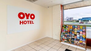 A hotel interior with a large 'OYO HOTEL' sign, a bulletin board with various items, and a view of buildings outside through a window.