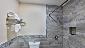 Een moderne badkamer met een douche, toilet en een handdoekrek.