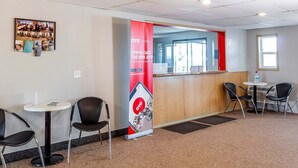 A hotel reception area with a red banner, a bulletin board with photos, and a reception desk.