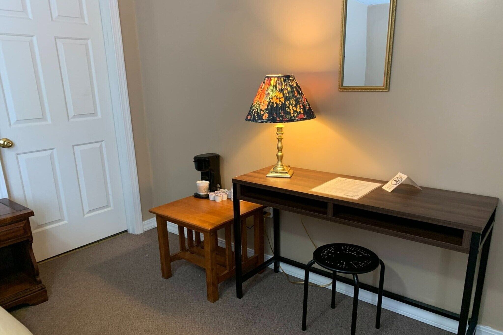 A small desk with a lamp, a chair, and a coffee maker.