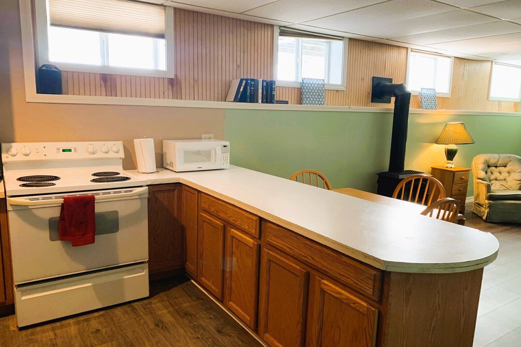 A compact kitchen with a stove, microwave, and wooden cabinets.