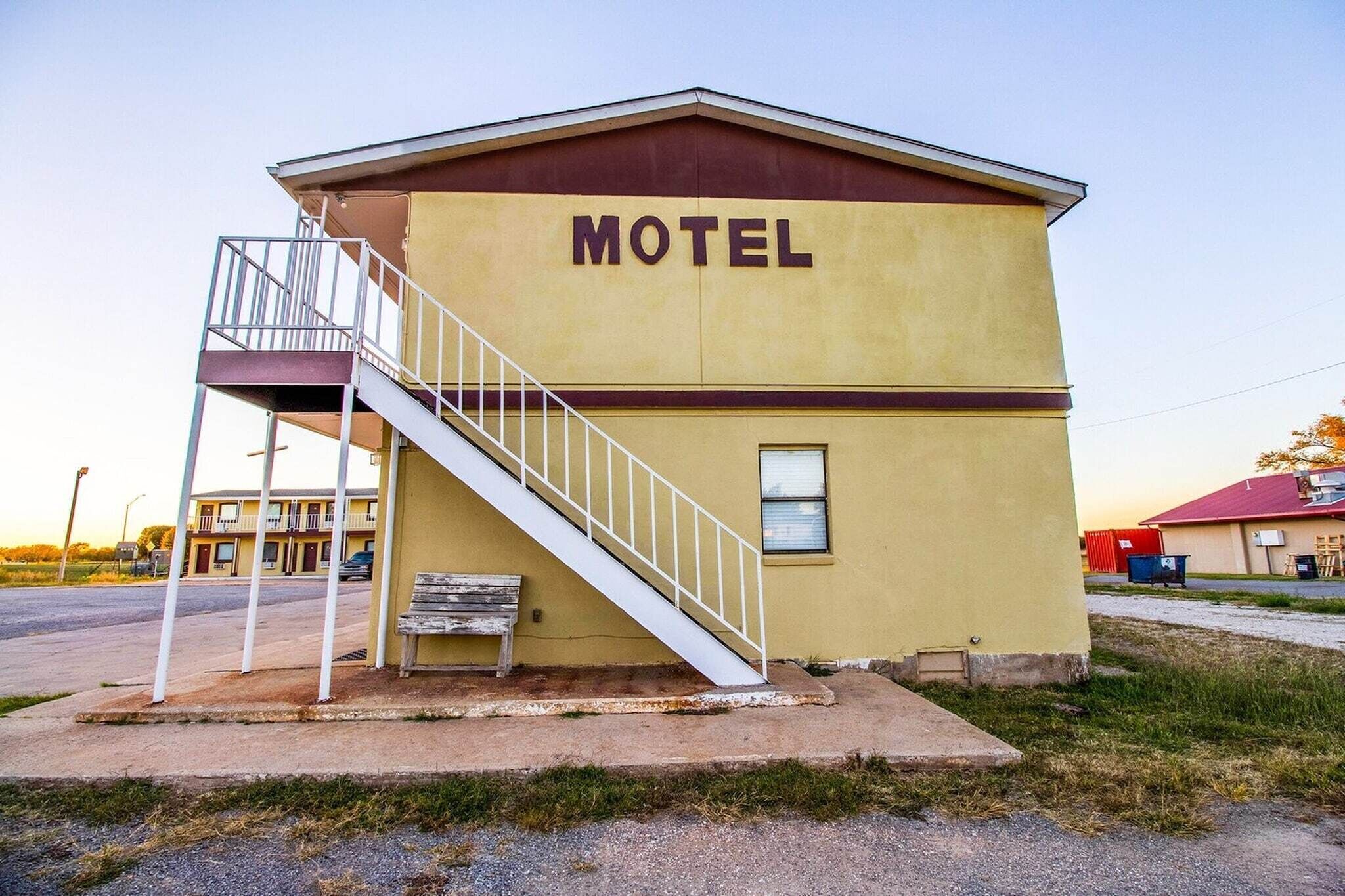A motel with a staircase, a bench, and a small window.