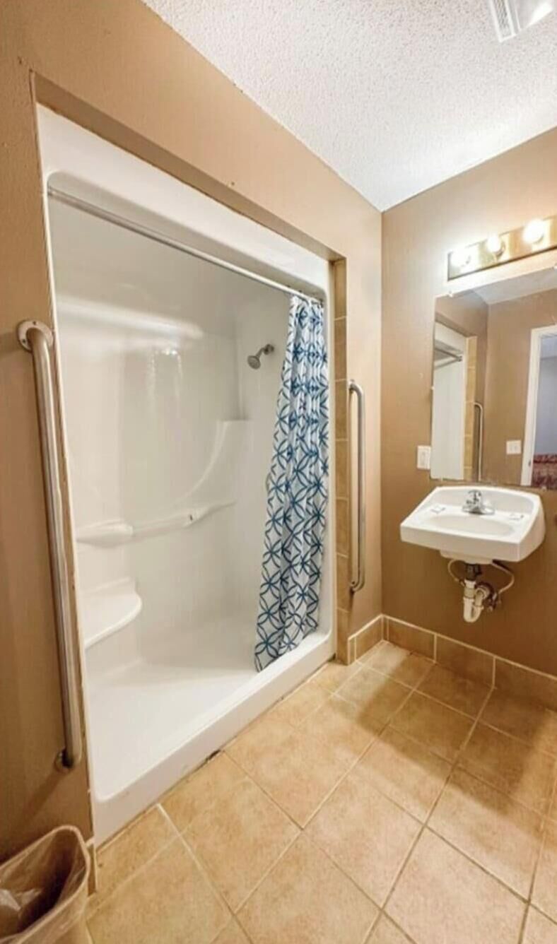 A bathroom with a walk-in shower, a sink, and a mirror with lights.