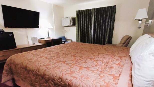 Une chambre d’hôtel avec un grand lit, un bureau avec une lampe, une télévision et une chaise.