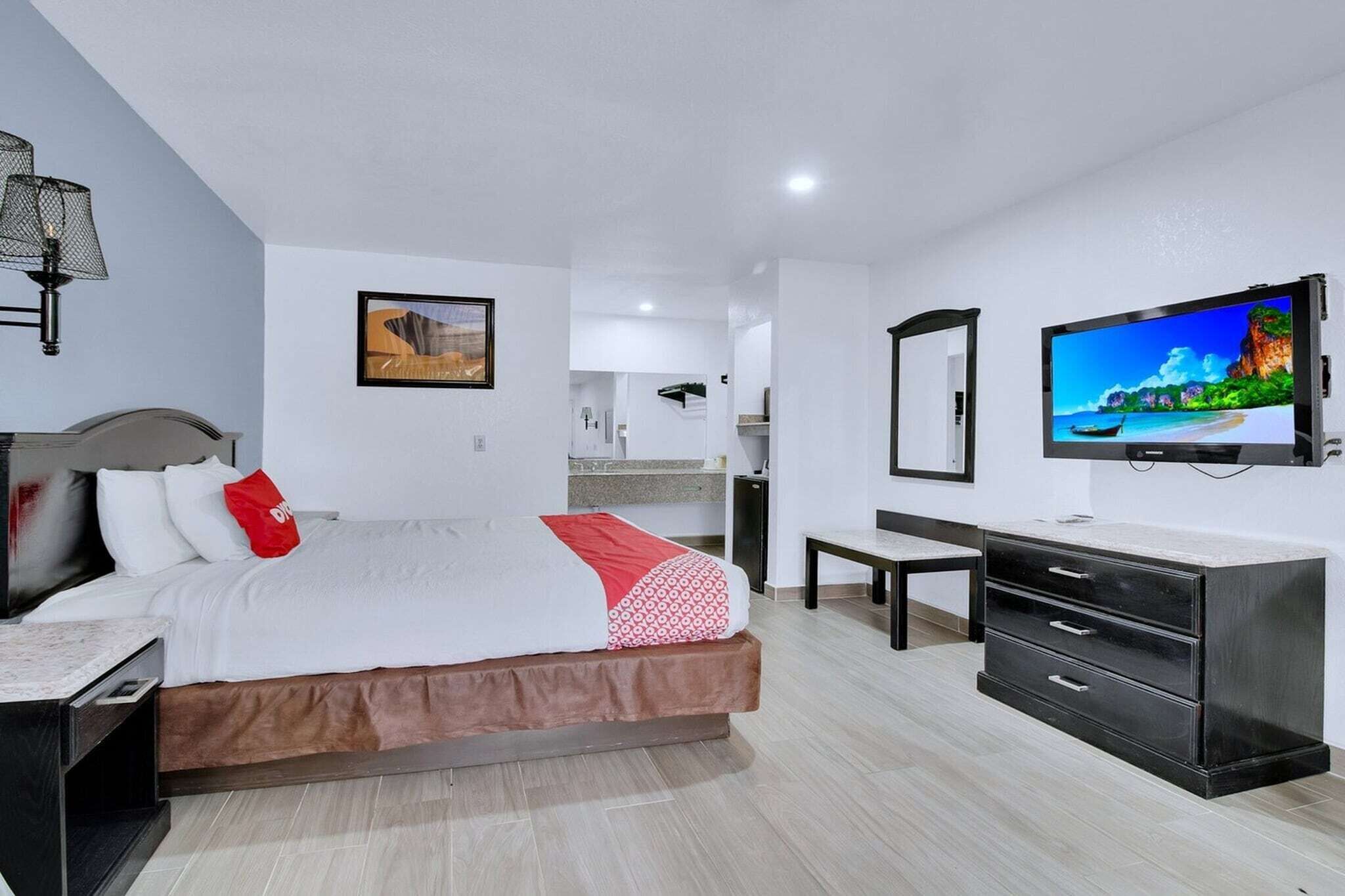 Een hotelkamer met een bed, een bureau, een dressoir, een televisie en een badkamer op de achtergrond.