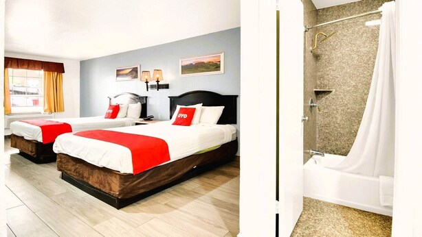 A hotel room with two beds, a shower, and a view of the street.