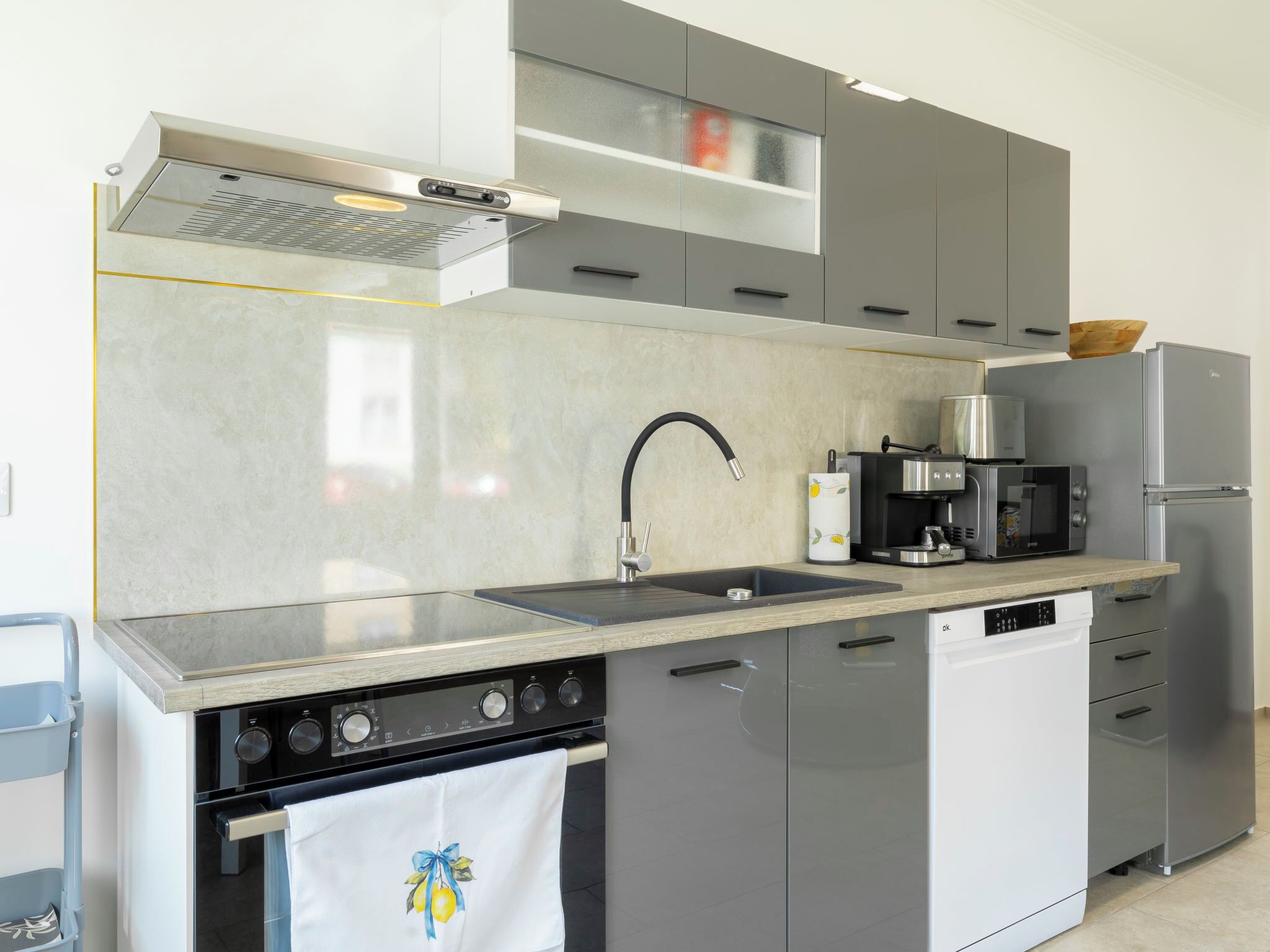 Eine moderne Küche mit Einbauofen, Kaffeemaschine, Mikrowelle und Kühlschrank.