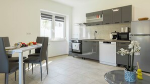 Una cocina moderna con comedor, que incluye un refrigerador, microondas, horno y una pequeña mesa de comedor con sillas.