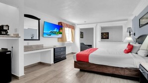 A modern hotel room with a bed, a desk, a TV, and a window with curtains.