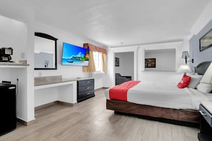 A modern hotel room with a bed, a desk, a TV, and a window with curtains.
