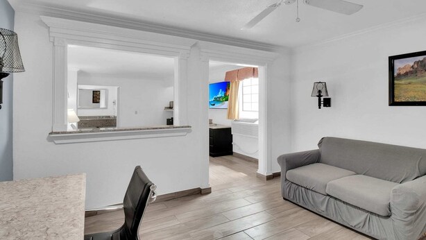 A spacious living area with a gray sofa, a dining table, and a ceiling fan.