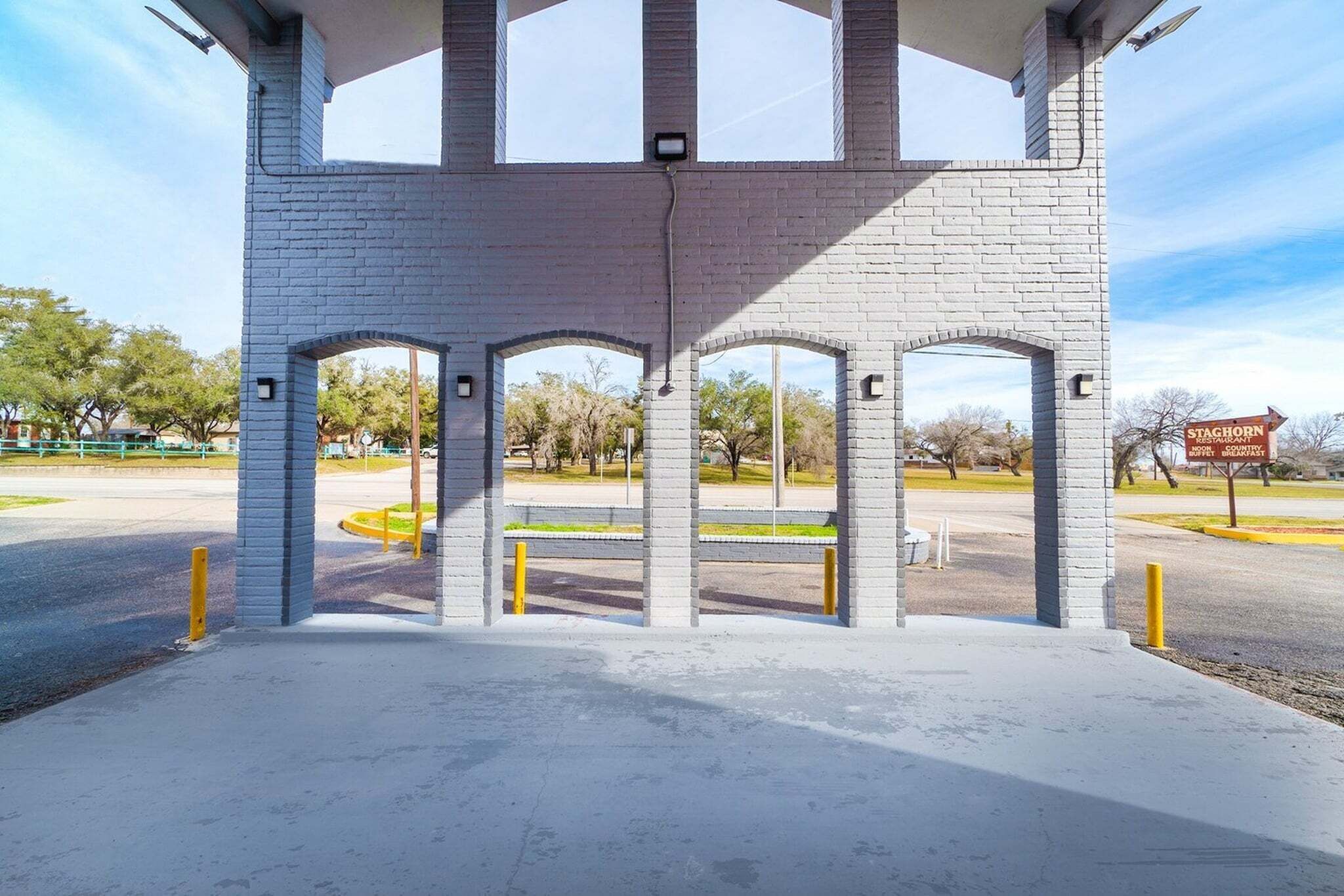 A brick structure with arched openings and a bench.