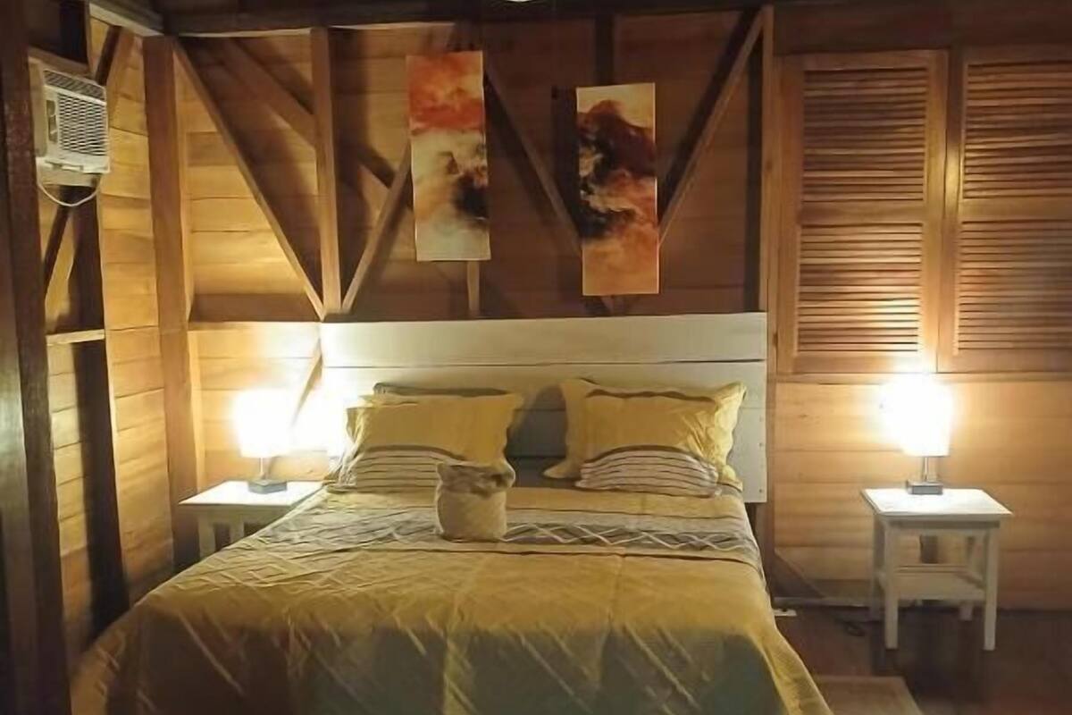 A wooden bedroom with a bed, two bedside tables, and a nightstand.