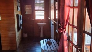 Un pasillo estrecho con paredes de madera, una pequeña mesa, un banco y una ventana con cortinas.