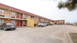 A motel with a row of rooms, a parking lot, and a few cars parked. - Tulsa| Relaxing 2 Full Beds (Tulsa)