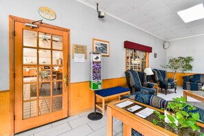 Um quarto aconchegante com porta de madeira, um banco, uma mesa com uma planta e um relógio fixado na parede.