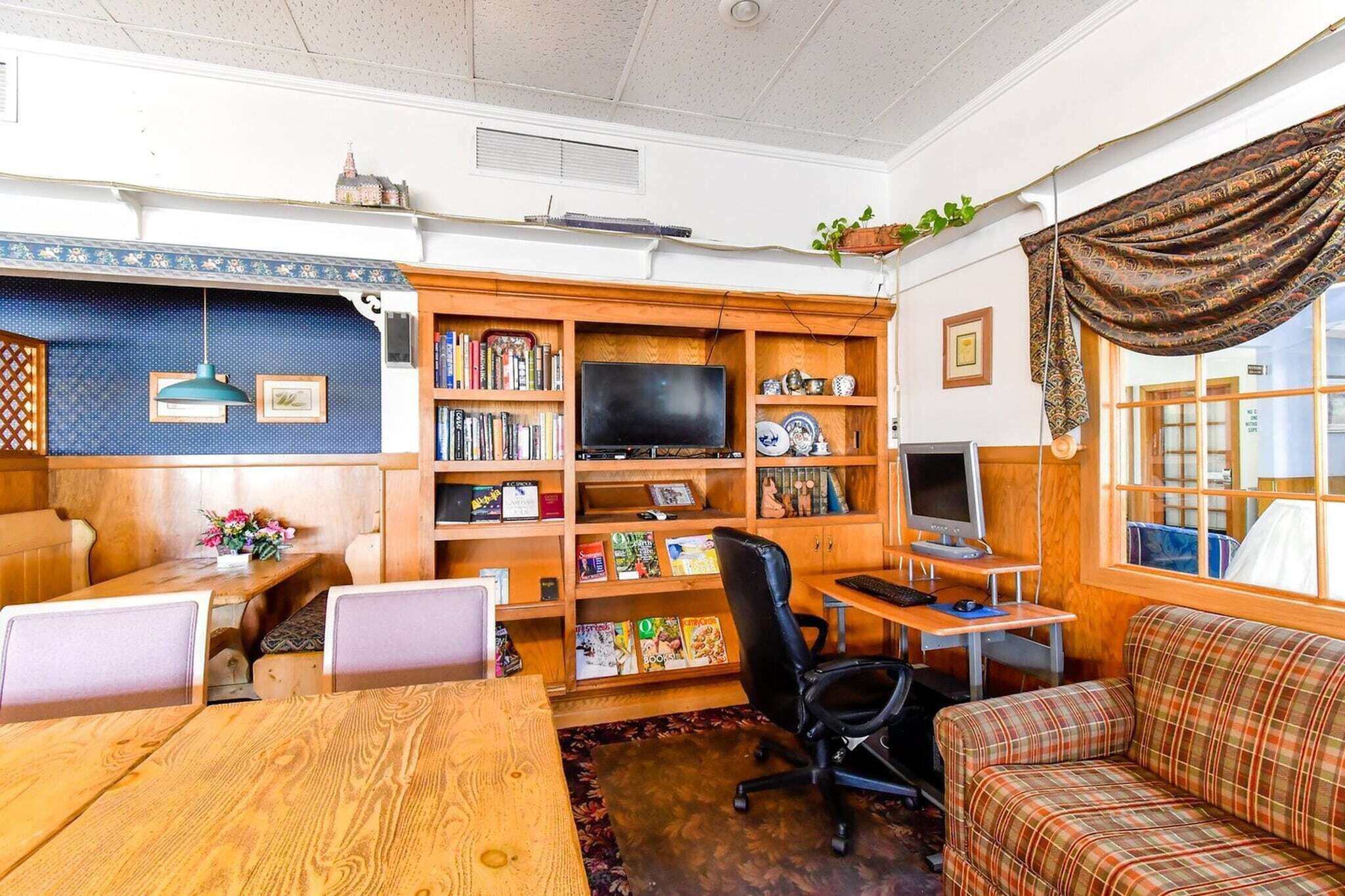 A cozy living room with a wooden bookshelf, a television, a dining table, and a sofa.
