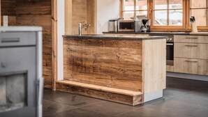 Een moderne keuken met een houten kookeiland, roestvrijstalen apparatuur en een groot raam.