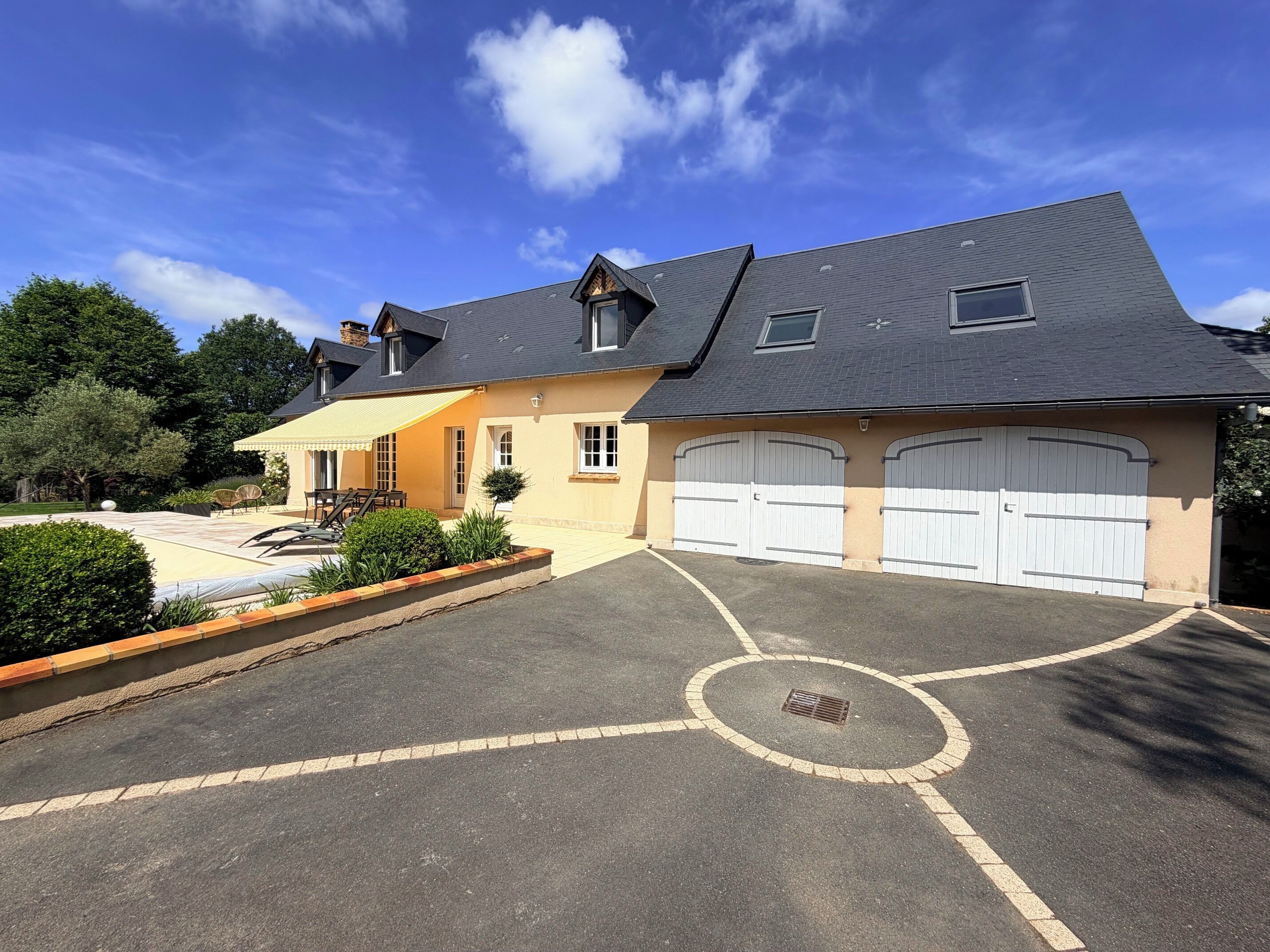 Ein zweistöckiges Haus mit Garage, Terrasse und Auffahrt.
