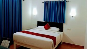 A bed with white bedding and a red pillow, blue curtains, and two wall-mounted lights.