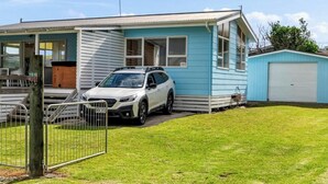 Ein einstöckiges Haus mit einem geparkten Auto vor der Tür, einer kleinen Veranda und einer Garage.