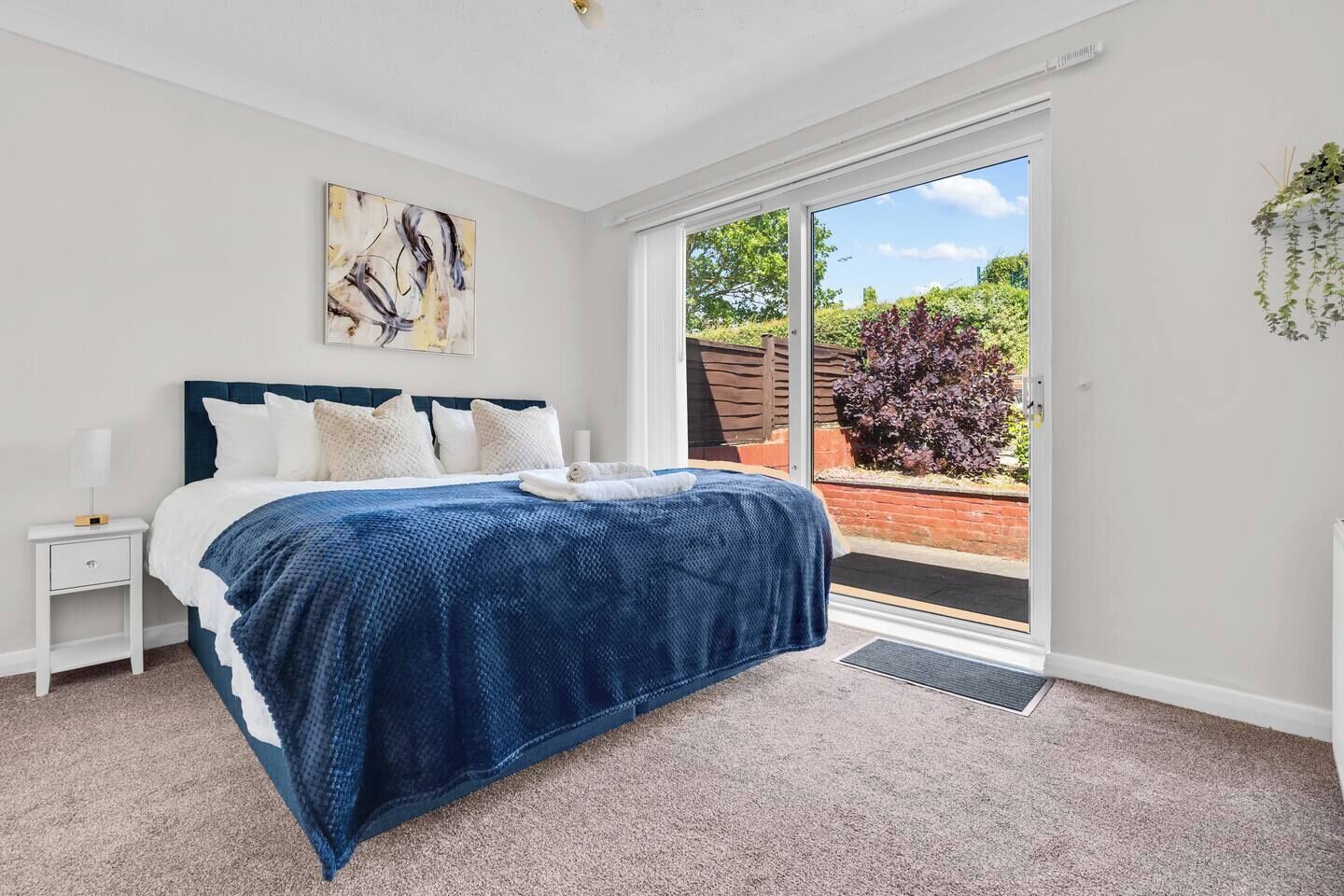 A bedroom with a bed, a nightstand, a window, and a door leading to an outdoor area.