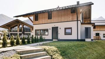 A modern two-story house with a wooden exterior, large windows, and a well-maintained lawn.
