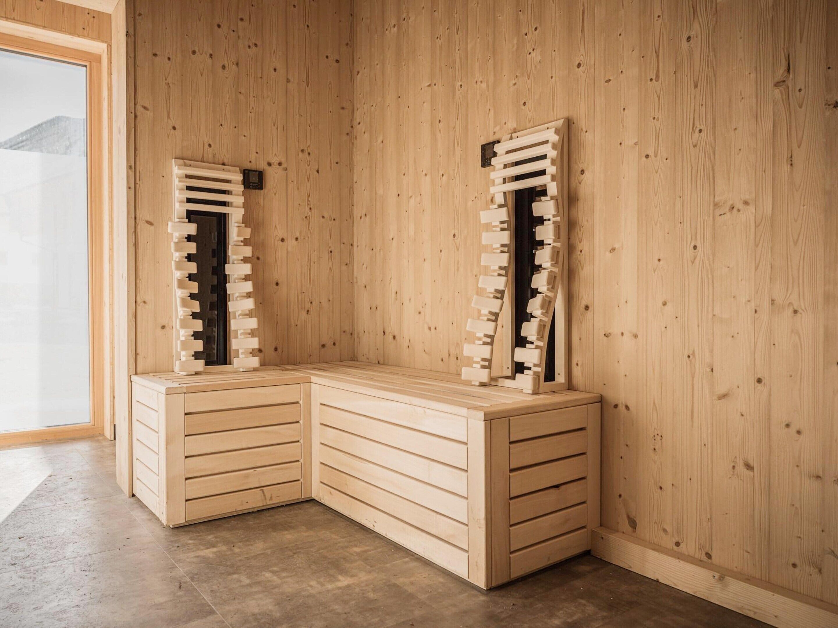 A corner room with wooden walls, a built-in bench with drawers, and a window with a view of a mountain.
