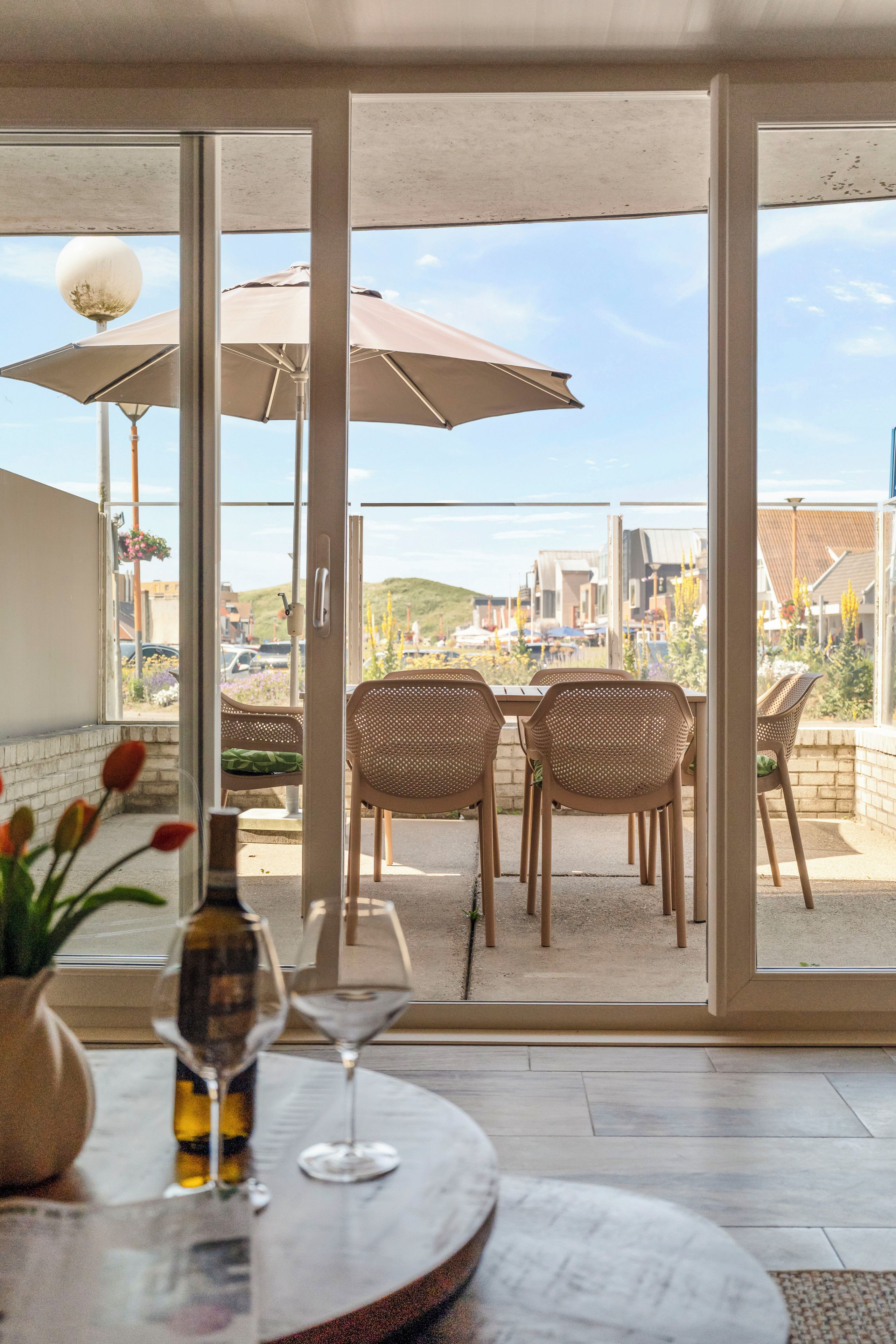 A dining area with a table, chairs, and a view through large glass doors.
