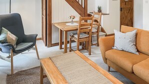 Ein Wohnzimmer mit einem Holzesstisch, Stühlen, einer Couch, einer Bank und einer Treppe.