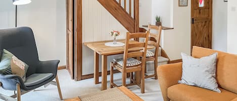 Een woonkamer met een houten eettafel, stoelen, een bank, een lange bank en een trap.