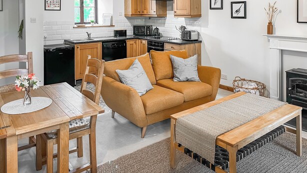 Eine moderne Küche mit Holzschränken, ein Essbereich mit Sofa und Tisch sowie ein Kamin.