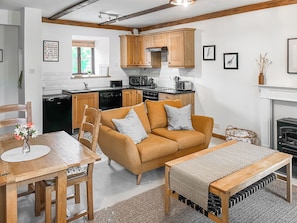 A modern kitchen with wooden cabinets, a dining area with a sofa and table, and a fireplace.