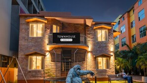 A building labeled 'Townhouse' with a company-serviced sign, a statue of a person, and a well-lit outdoor area with a bench and a trampoline. - Classic With Balcony Hotel Coral (Kanthi)