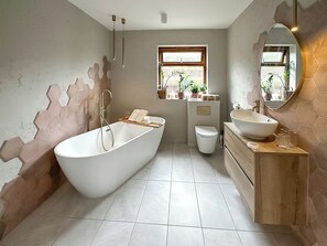 Ein modernes Badezimmer mit einer freistehenden Badewanne, einer Toilette und einem Waschtisch mit einem großen Spiegel.