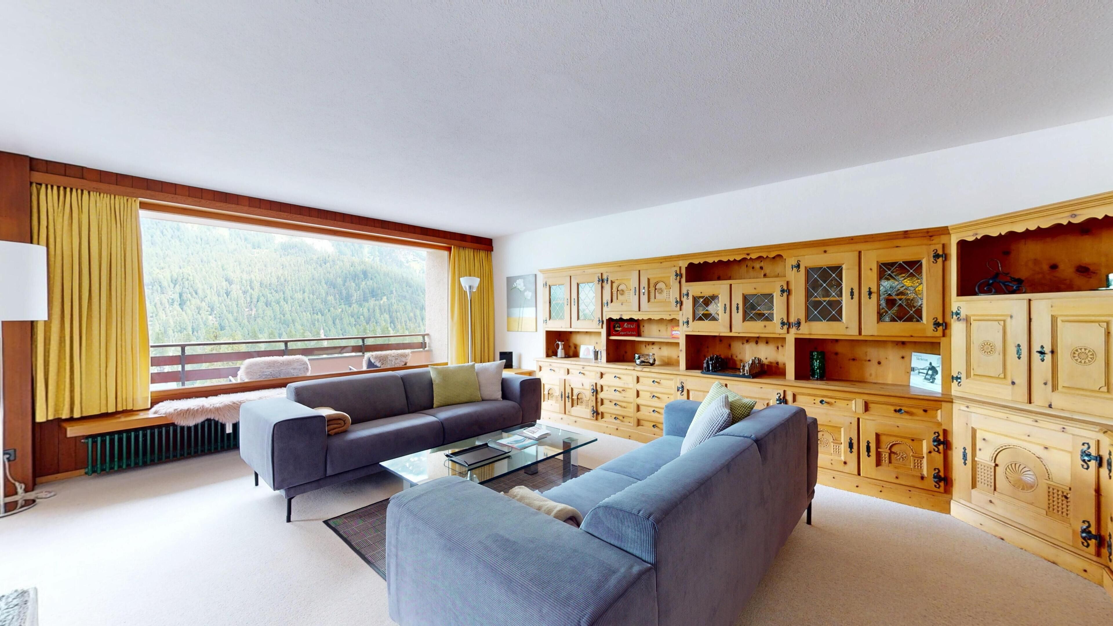 A spacious living room with two sofas, a coffee table, and a large window with a view of a forest.
