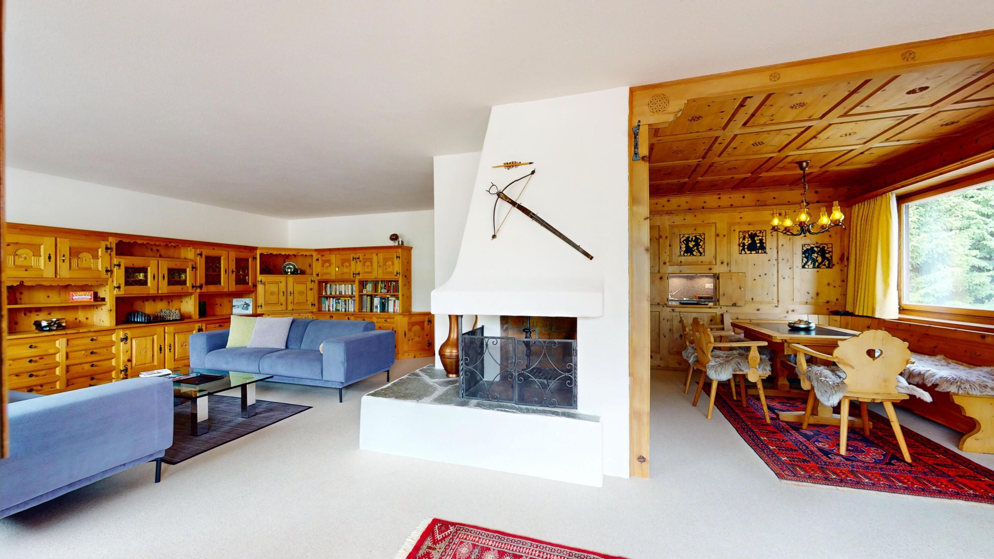 Ein Holzinnenraum mit einer Couch, Kamin, Essbereich und Holzkästen.