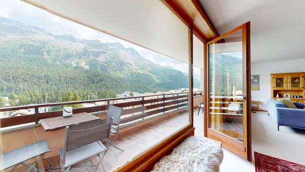 Un balcon avec une table et des chaises, un canapé et une vue sur les montagnes.
