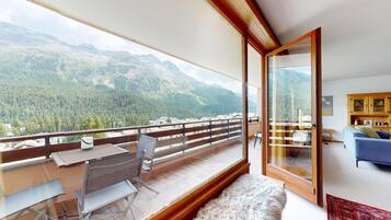 Ein Balkon mit Tisch, Stühlen, einer Couch und Blick auf Berge.