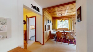 Un intérieur en bois comprenant un coin repas, une cuisine et un couloir menant à une autre pièce.